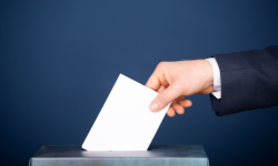 hand placing a paper into a ballot box